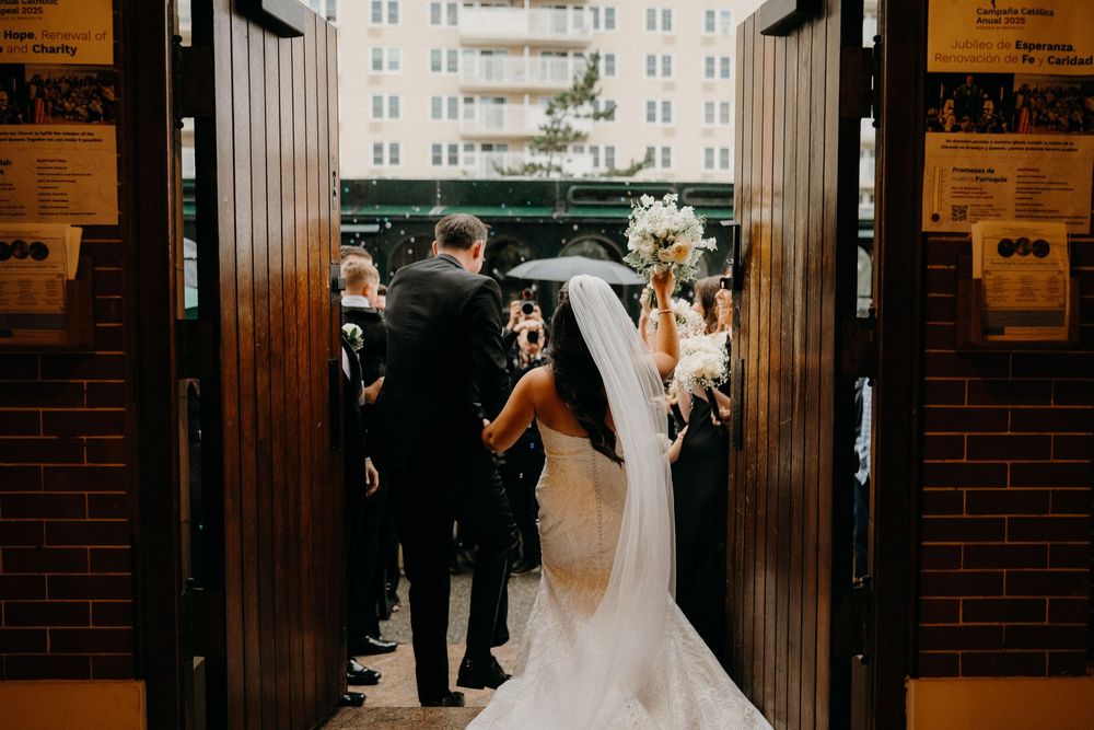 Wedding party members stand in a brick-lined hallway during an elegant indoor ceremony.