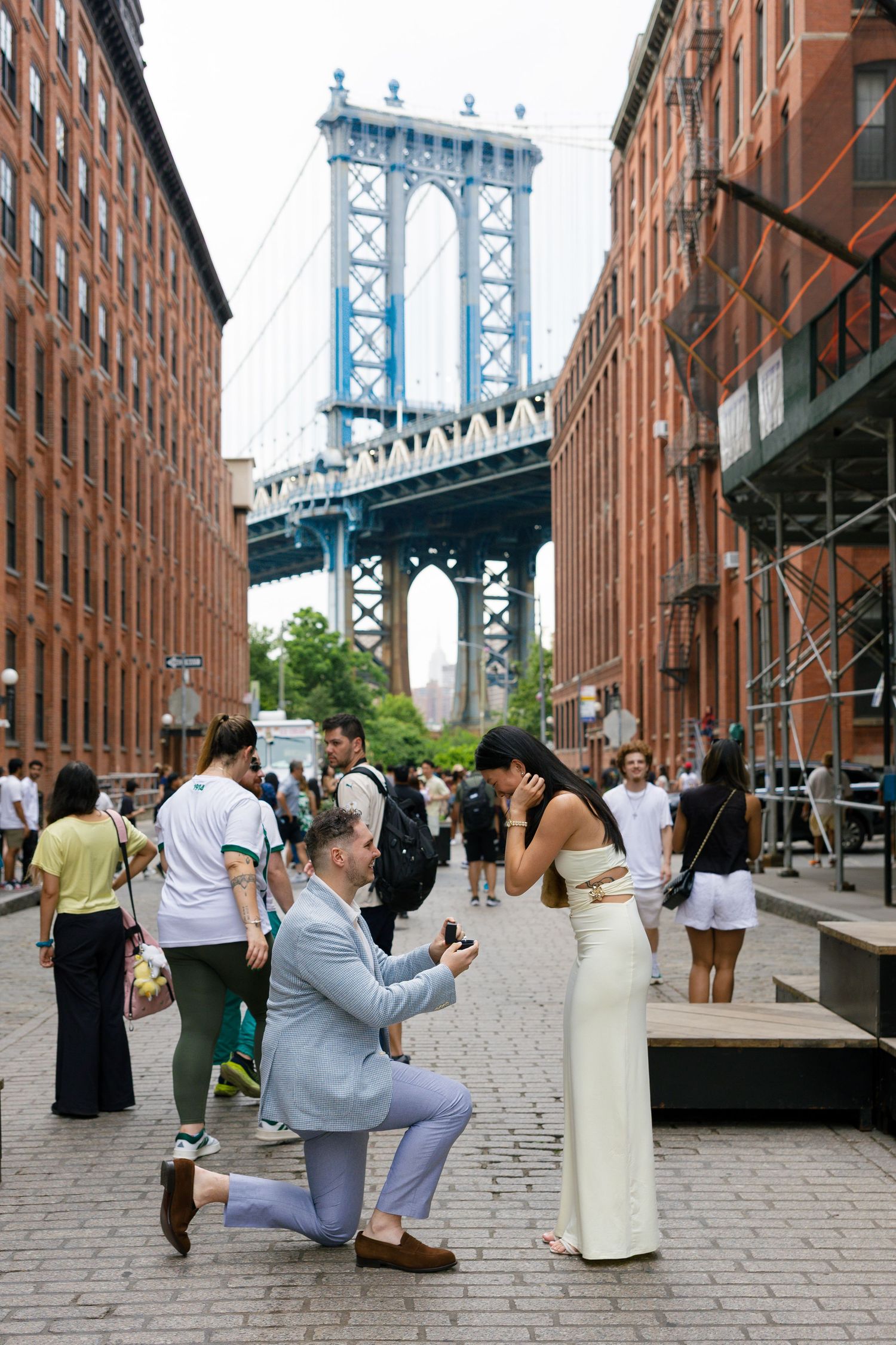 Sequence of photos showing a proposal moment on a cobblestone street with the Manhattan Bridge in the background.
