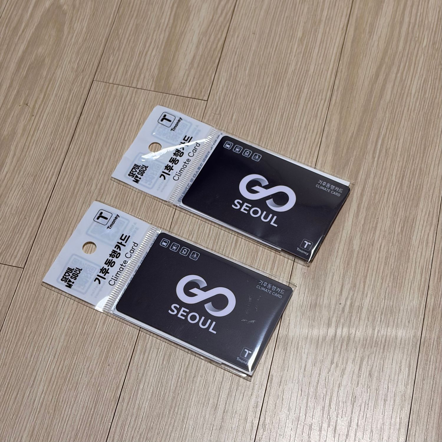 Black and white business cards arranged on a light wooden floor with Seoul branding visible.
