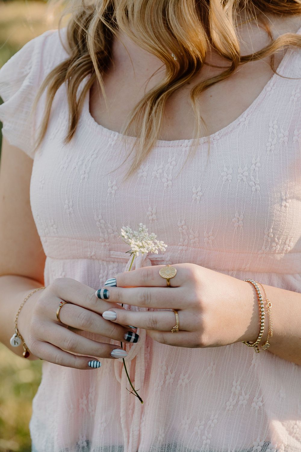 A sequence of close-up photos showing hands wearing multiple rings and bracelets against a white lace dress background.