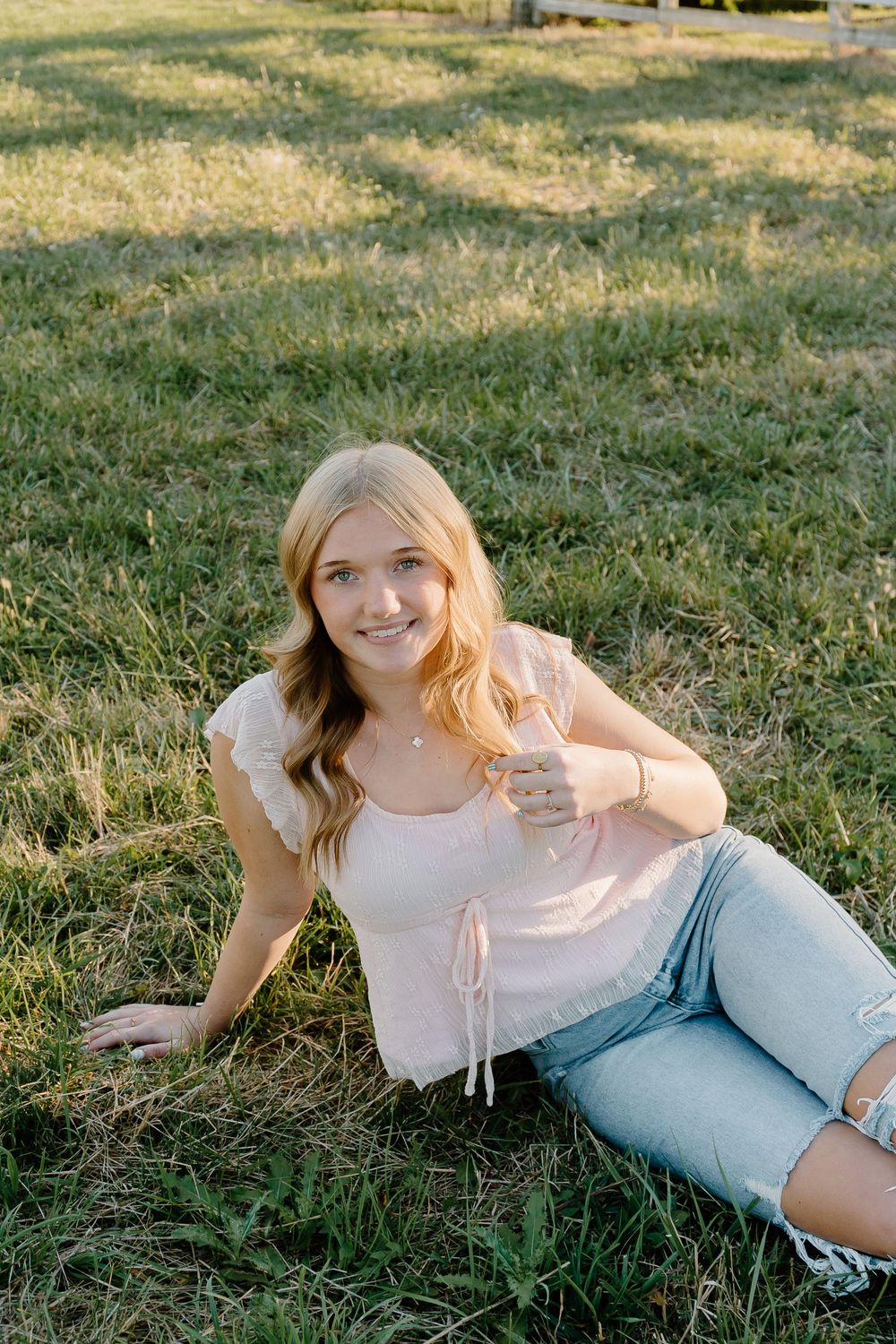 A series of outdoor portraits showing someone relaxing on grass wearing a white top and light blue jeans in warm sunlight.