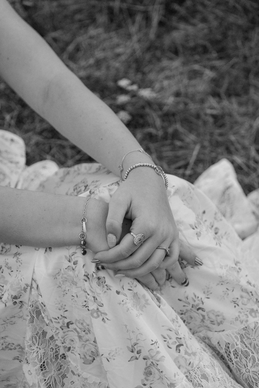 Close-up of hands delicately touching white lace fabric with floral patterns.