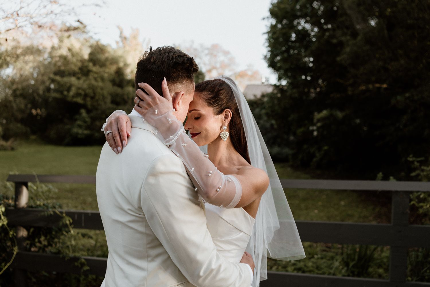 A couple in wedding attire embraces romantically outdoors during their Wairarapa elopement by August and Vine