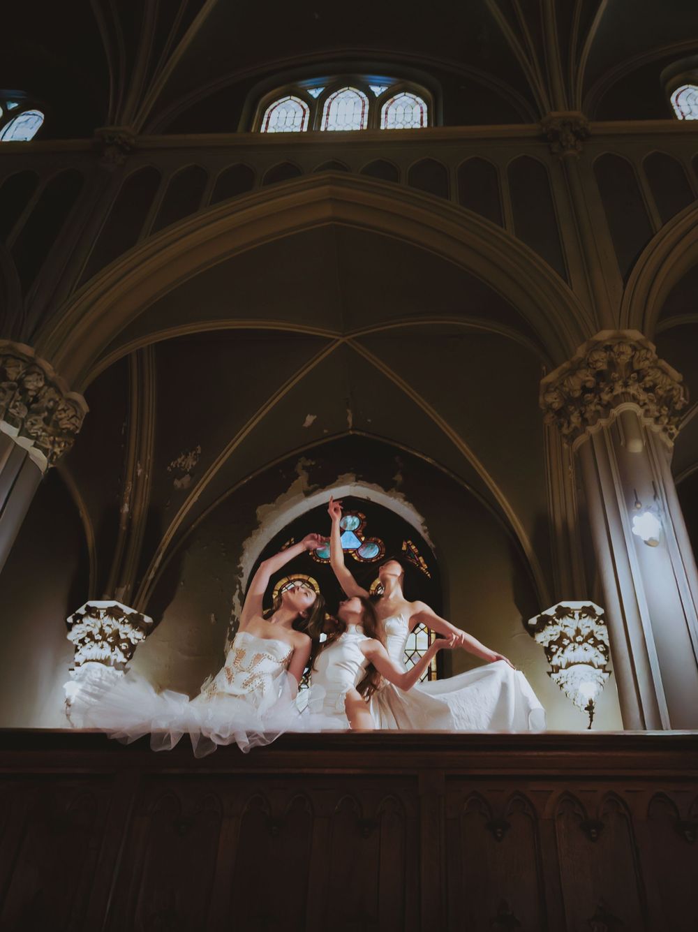 Silhouetted dancers performing against gothic church architecture and vaulted ceilings.
