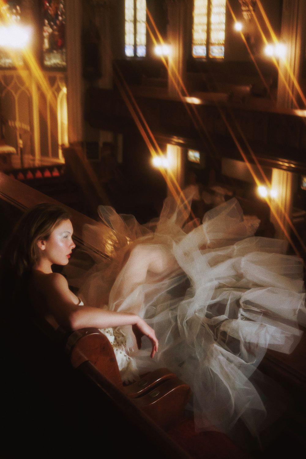Ethereal white tulle gown flows around a figure in dramatic lighting inside a gothic church interior.