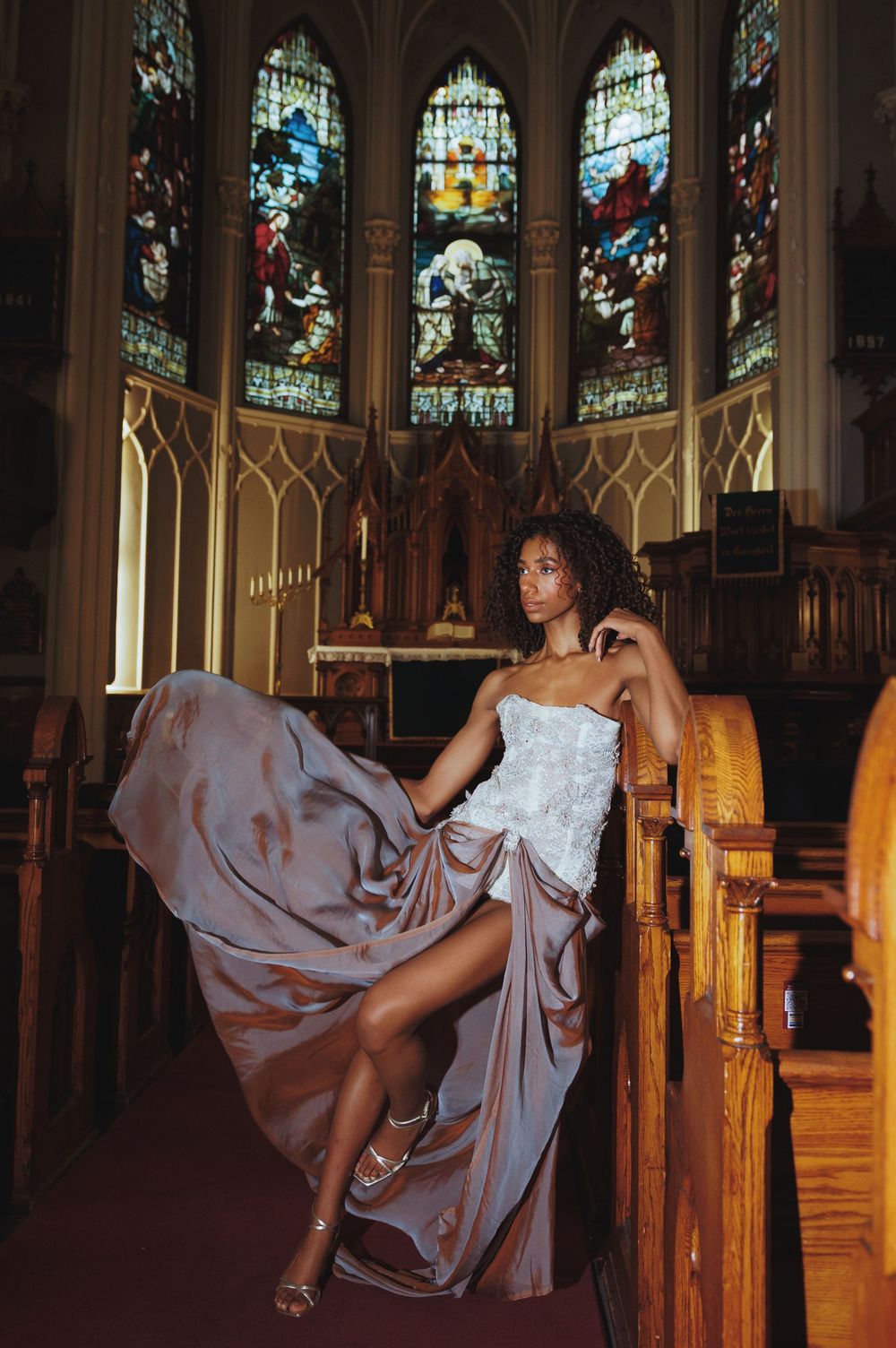 Fashion photo showing flowing dress movement against ornate church interior with stained glass.