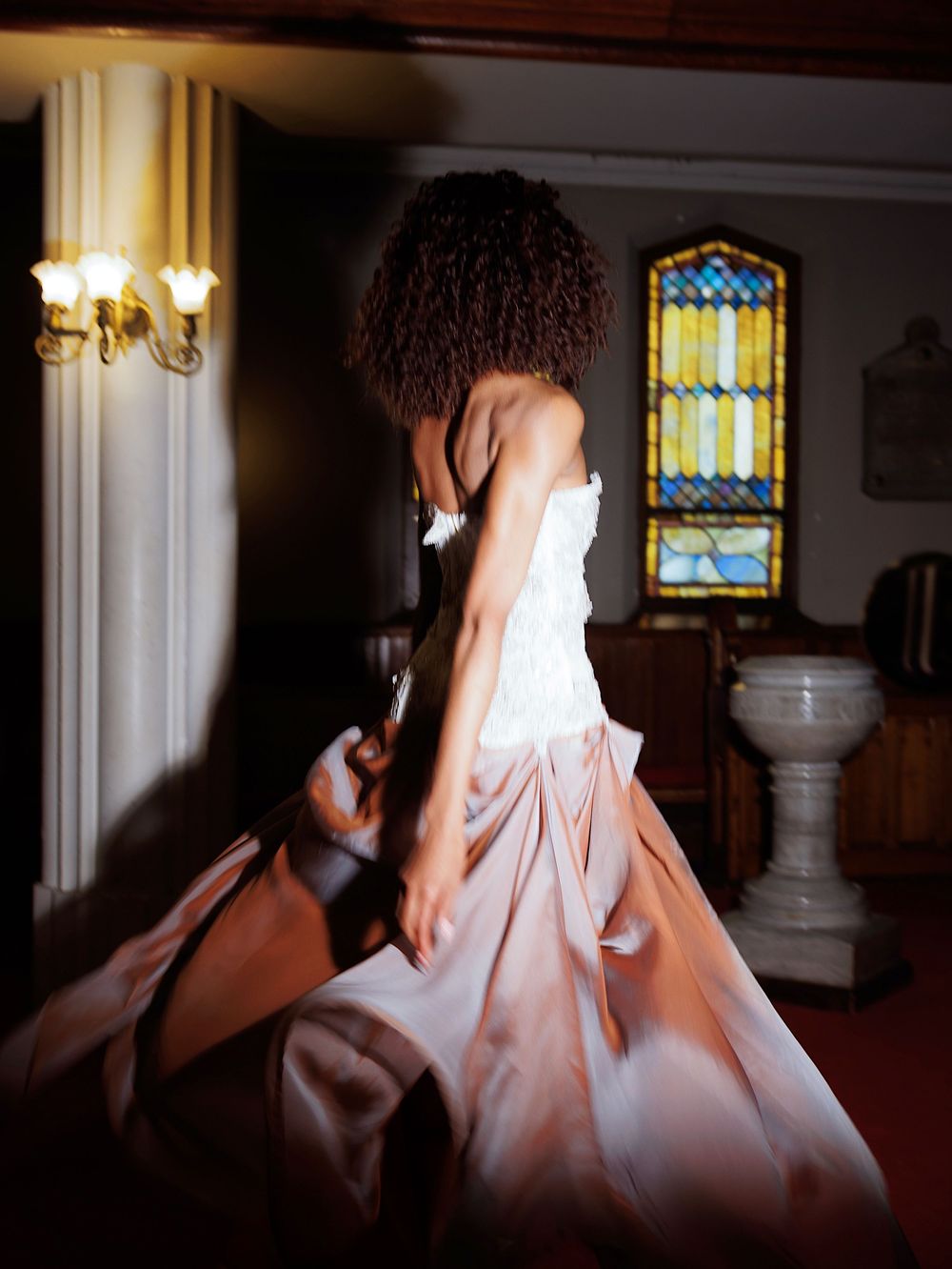 Artistic bridal portrait with soft backlighting in a historic church setting.