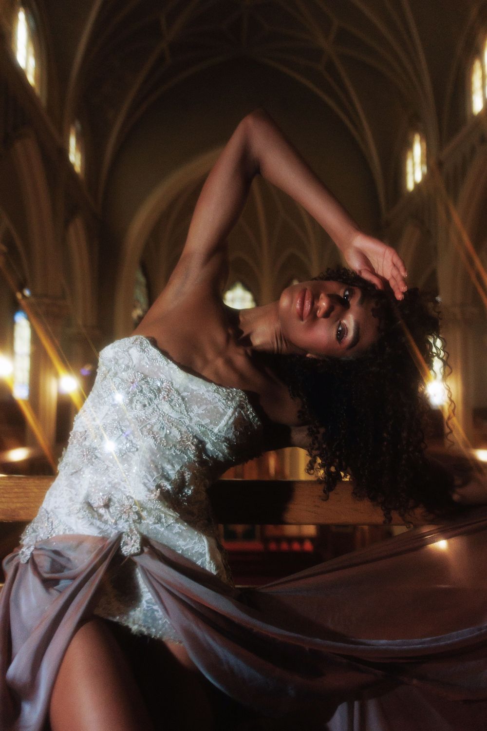 Elegant bridal portrait in a gothic church with dramatic lighting and flowing white gown.
