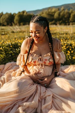 A joyful moment captured in a golden field of wildflowers during sunset, wearing a flowing peach-colored dress.