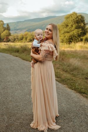 A tender outdoor photoshoot showing matching peach-colored dresses against a scenic mountain backdrop.