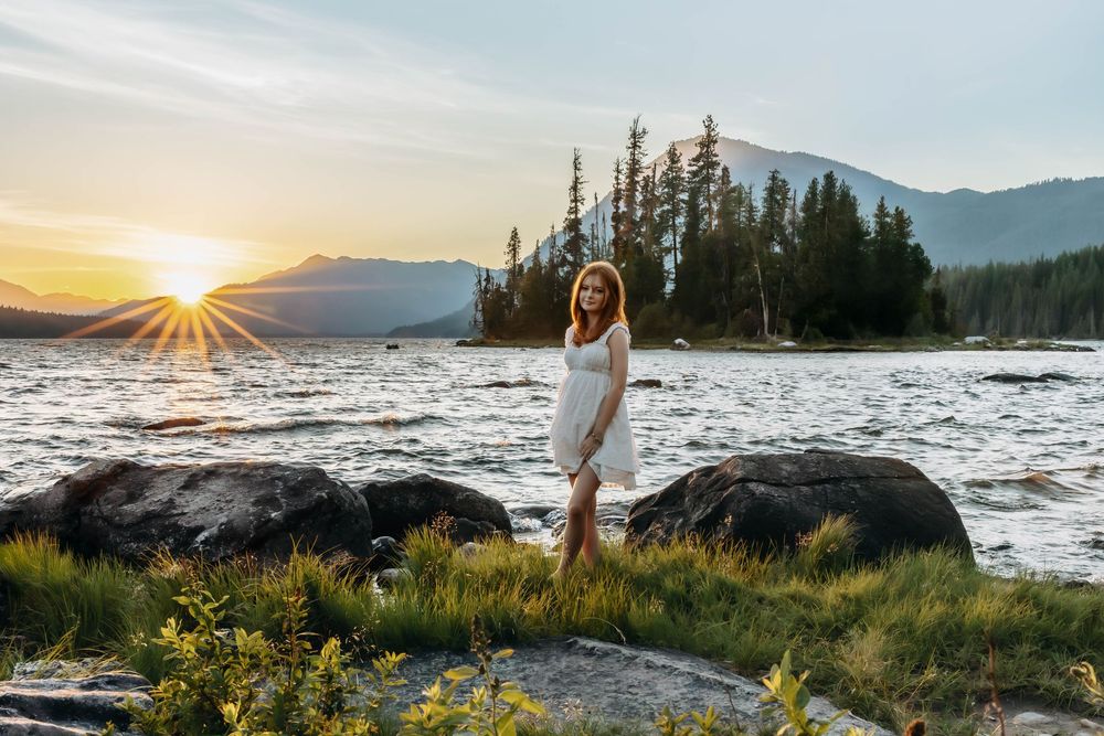 Scenic sunset over mountain lake with evergreen trees along shoreline.
