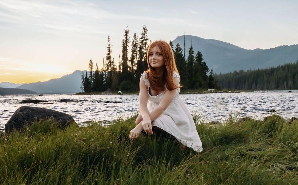 Serene lakeside portrait with mountains and evergreens during sunset.