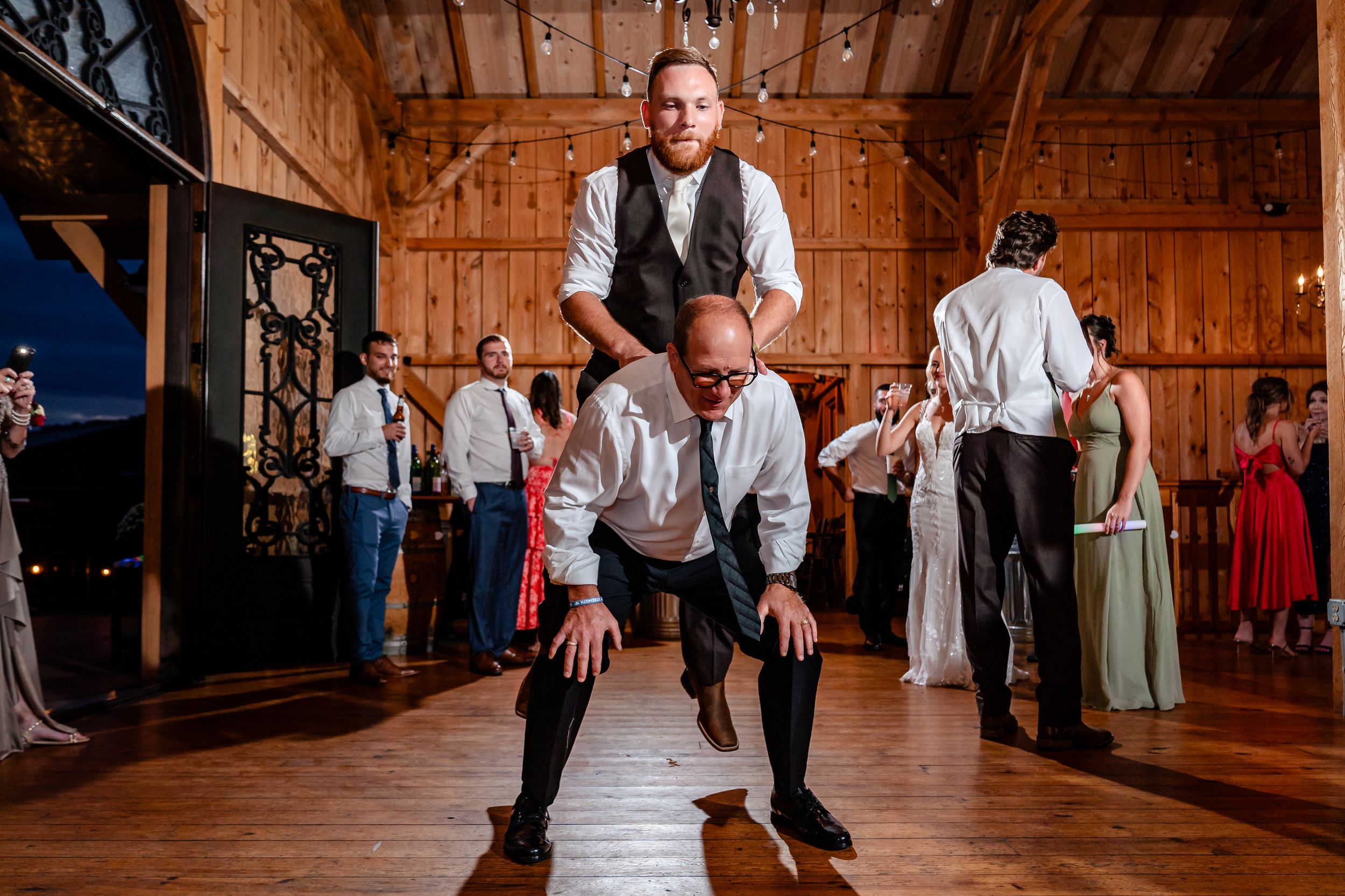 Couples dancing on wooden floor during rustic barn wedding reception.