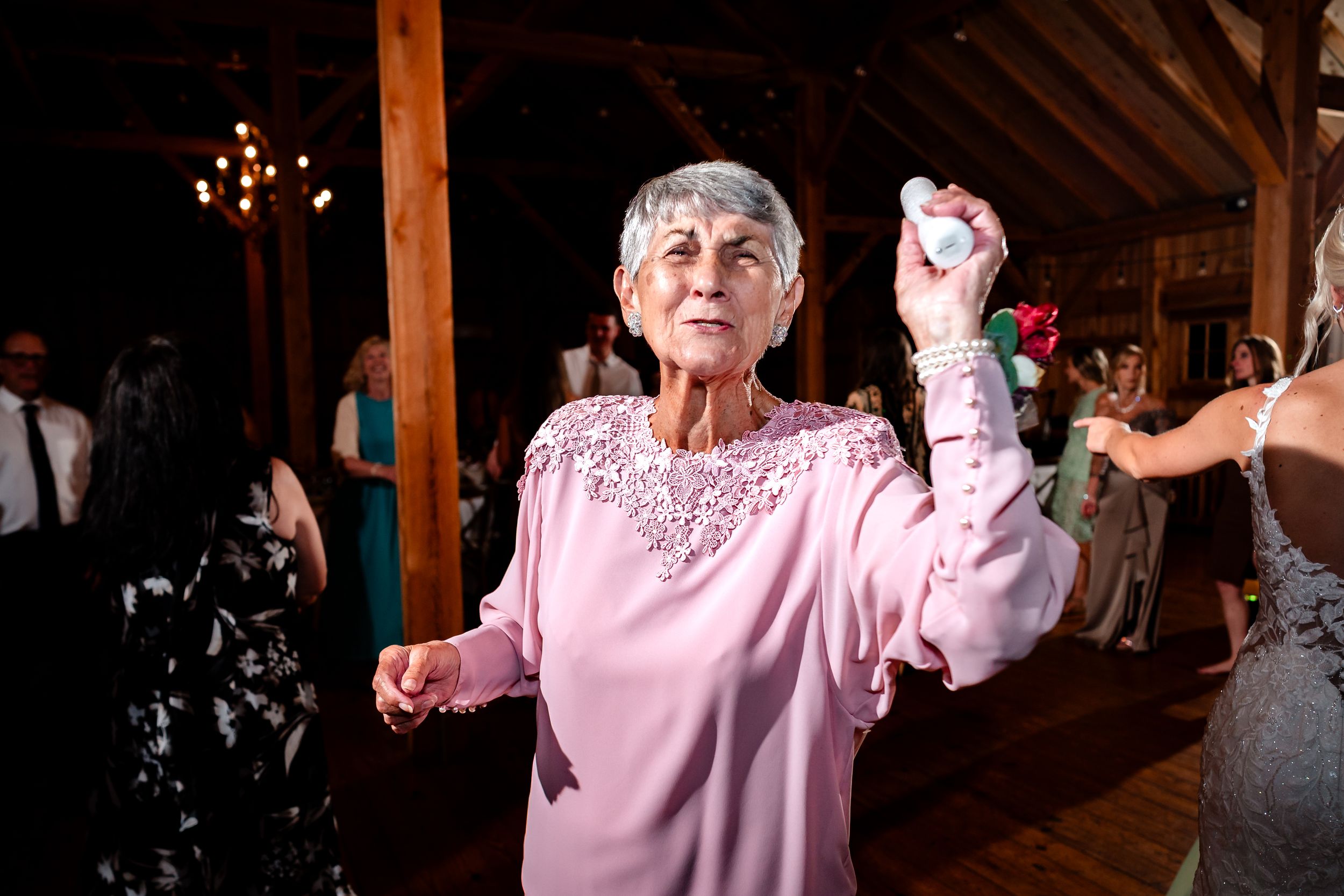 Wedding guests enjoying dance floor at rustic barn reception with warm lighting.