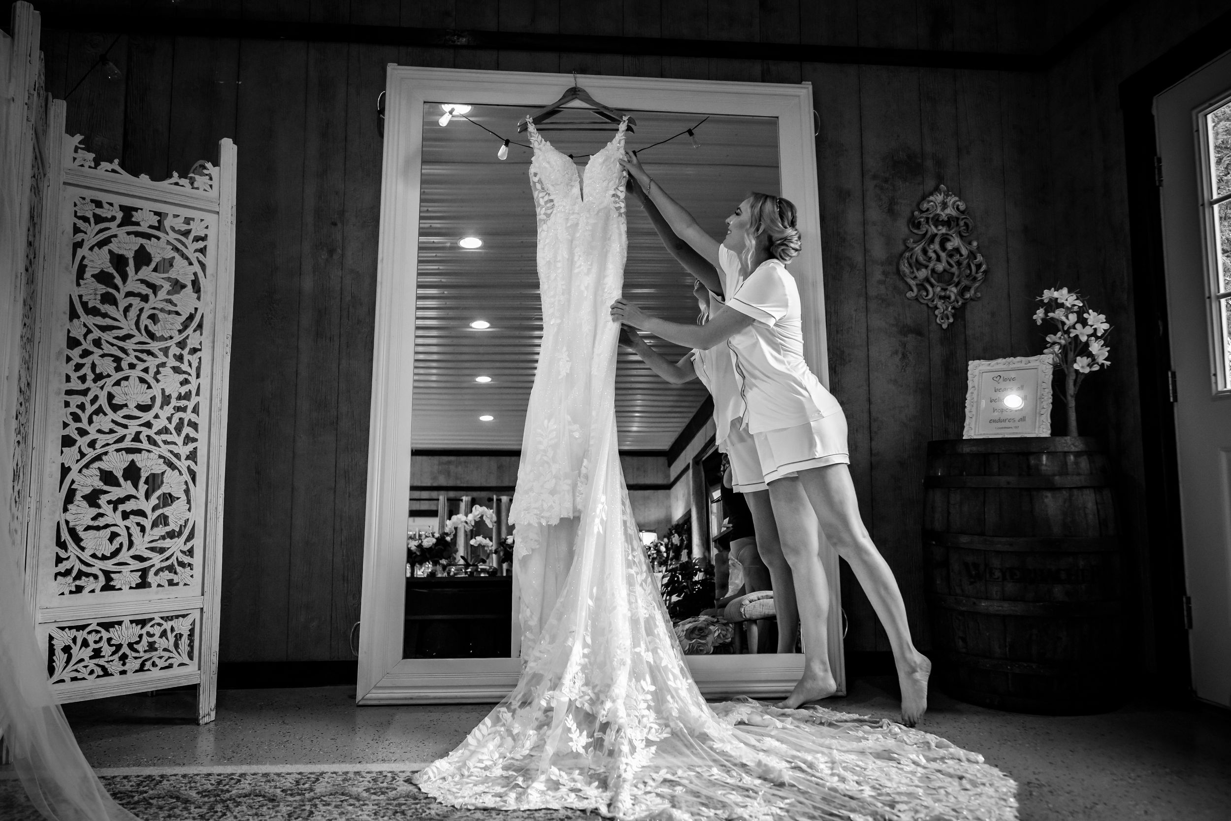 A white lace wedding dress being displayed against decorative wooden panels.