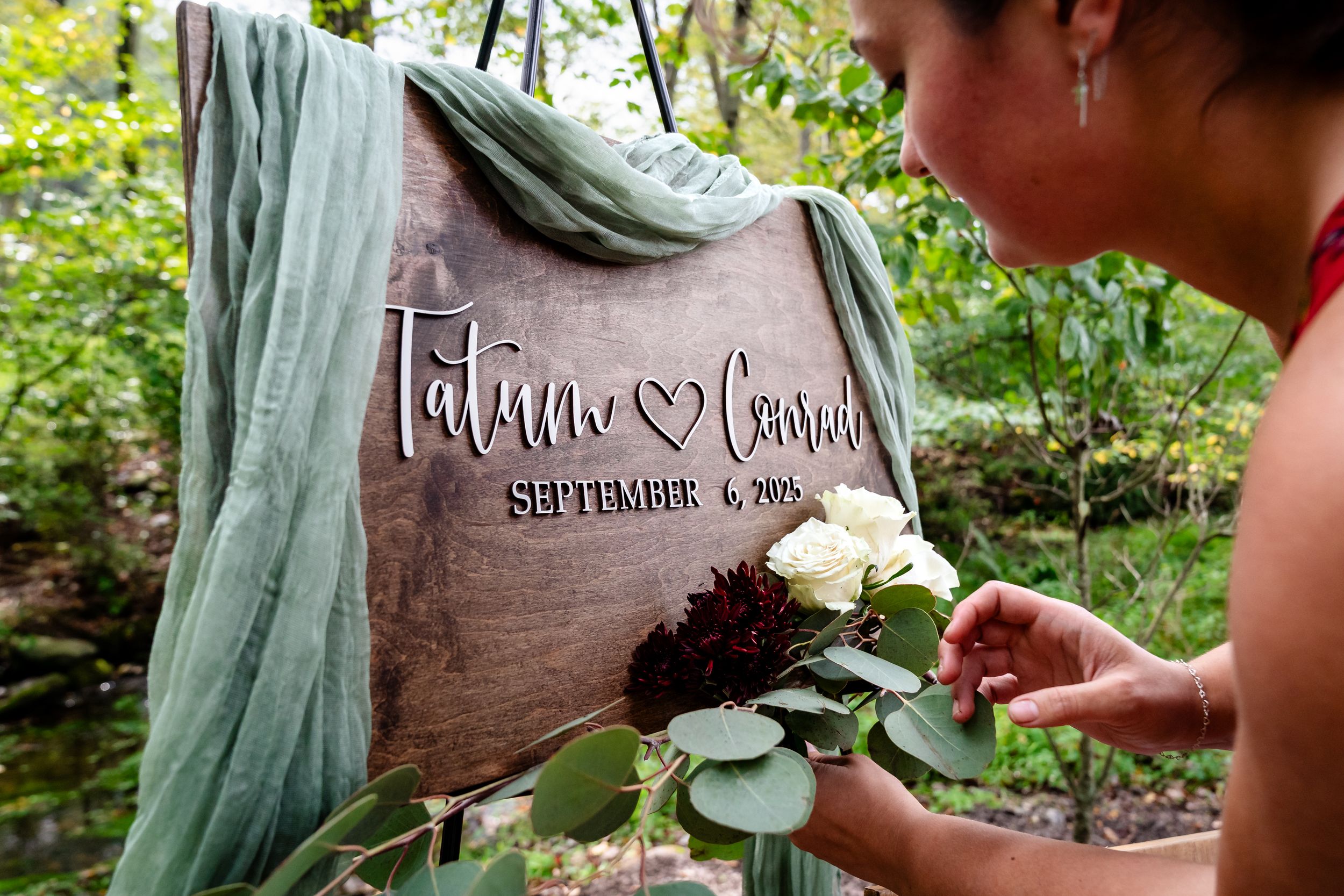Wedding details featuring sage green decor and rustic wooden signage.