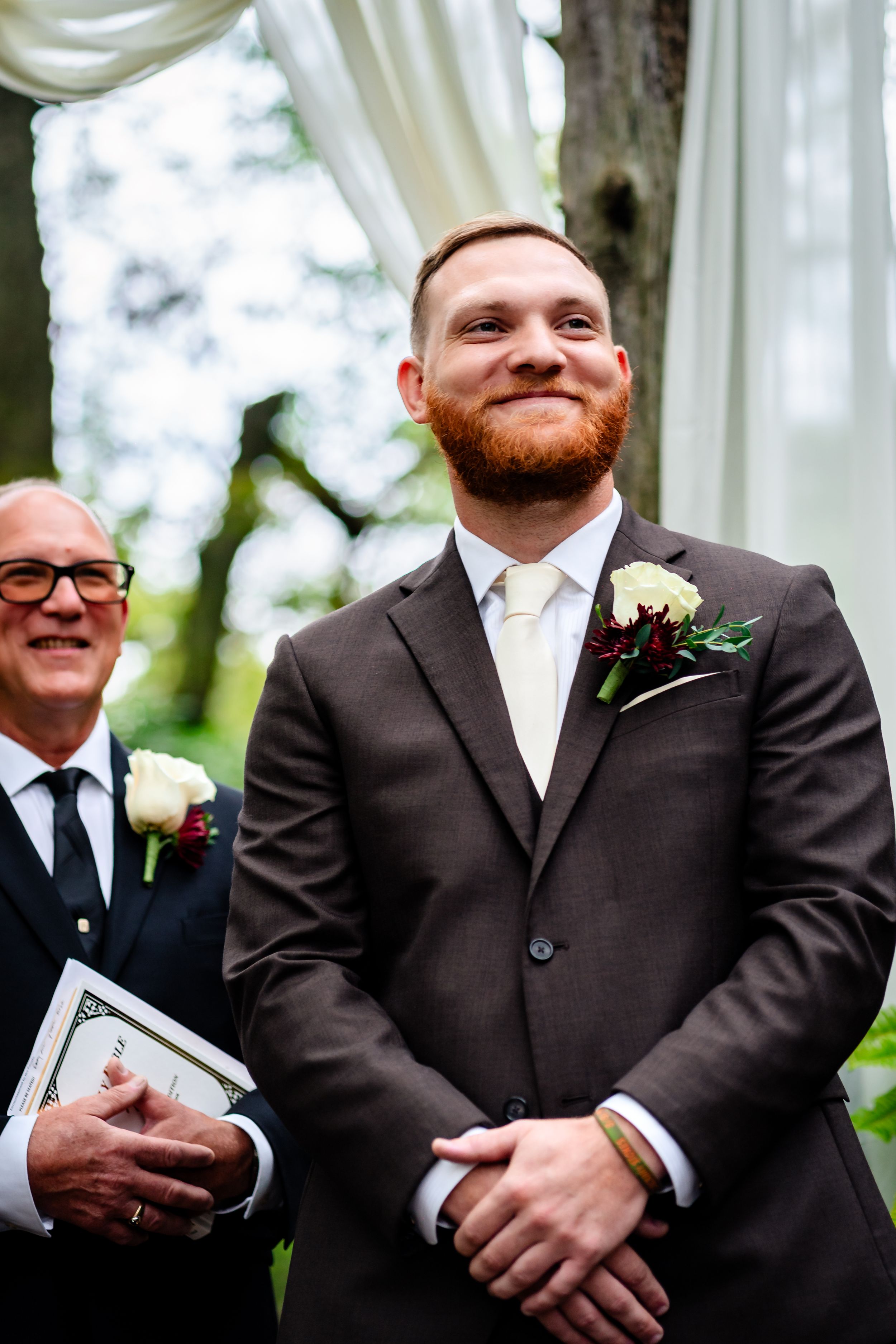 Wedding party members in formal attire standing together during outdoor ceremony.
