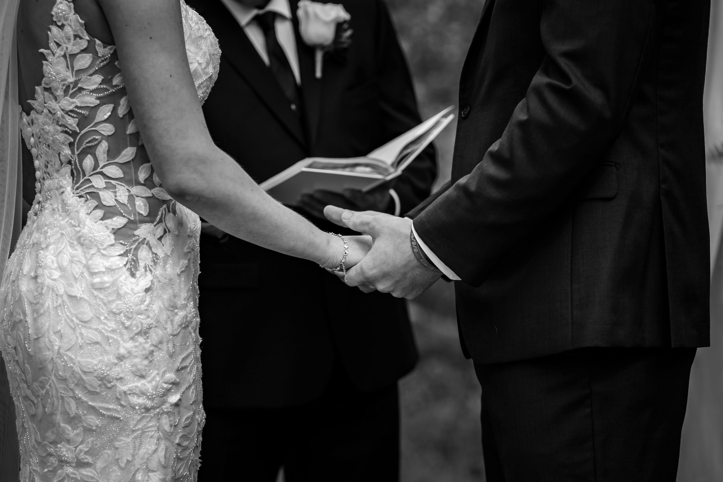 Black and white capture of wedding ceremony details with lace dress and formal attire.