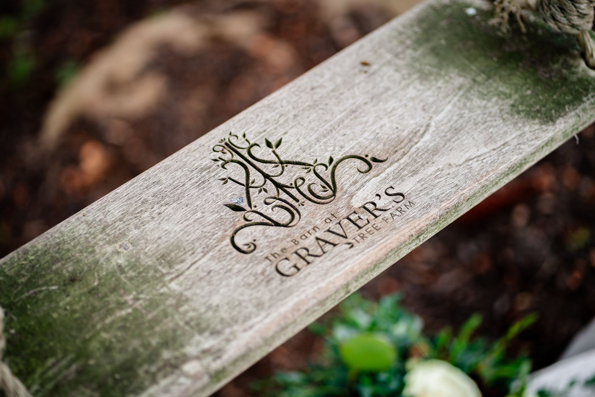 Rustic wooden signs with elegant calligraphy text in an outdoor garden setting.