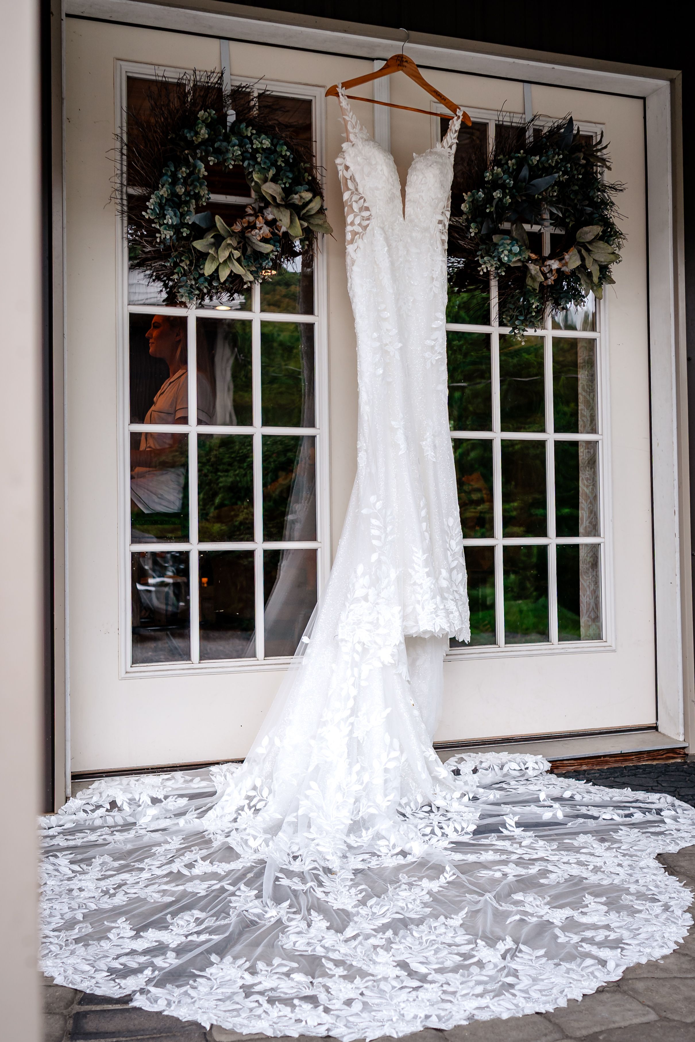 Beautiful white lace wedding dresses with long trains displayed in front of windows.