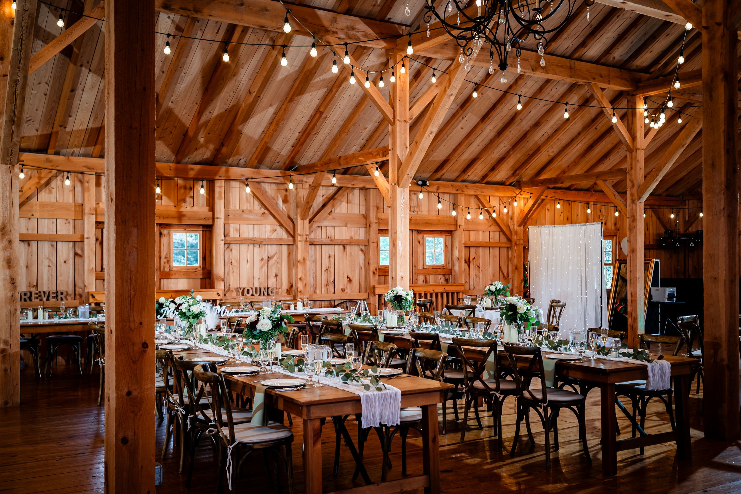 Rustic barn wedding reception venue with exposed wooden beams and elegant table settings.