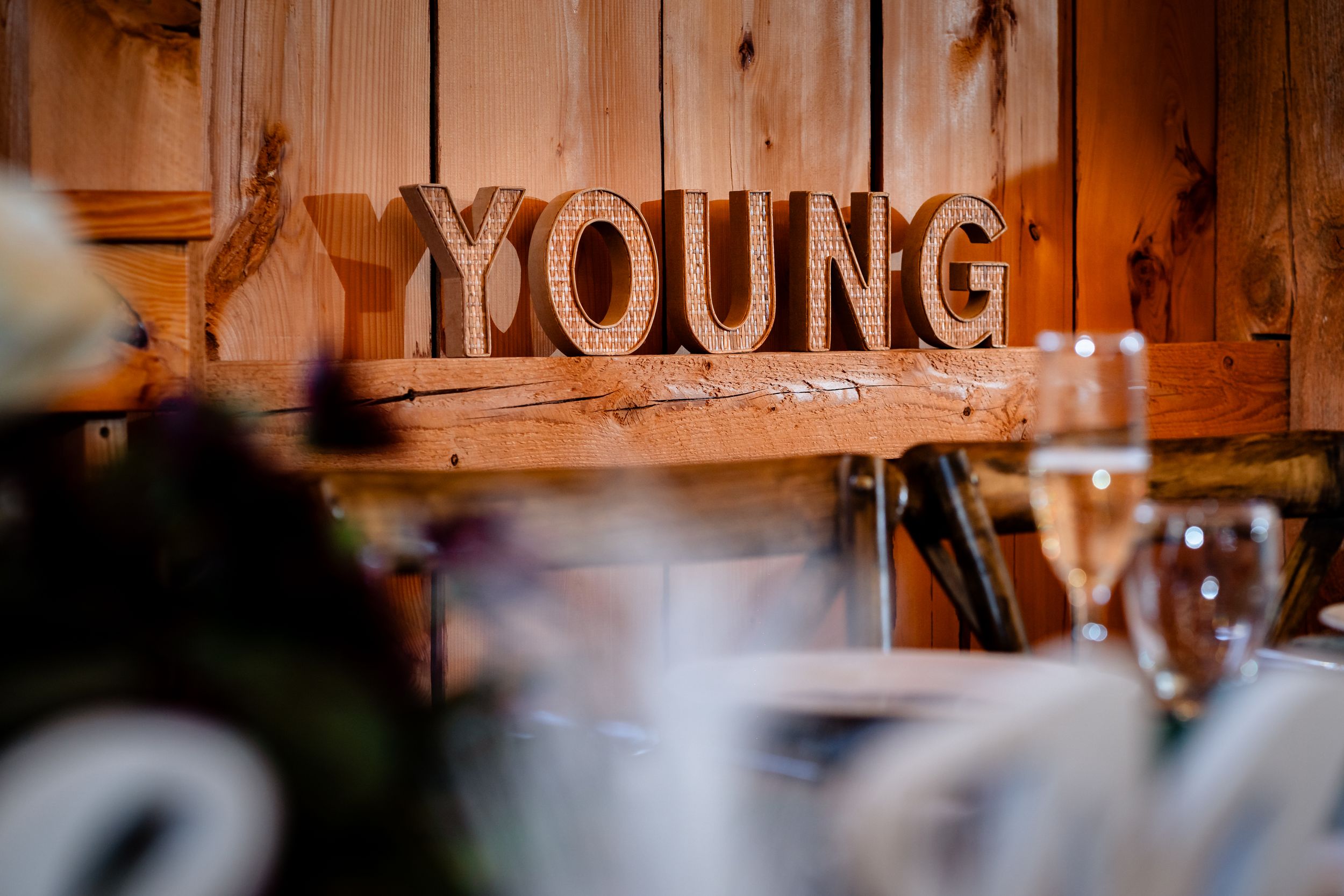 Wooden wedding venue interior with custom name signage and elegant table settings.