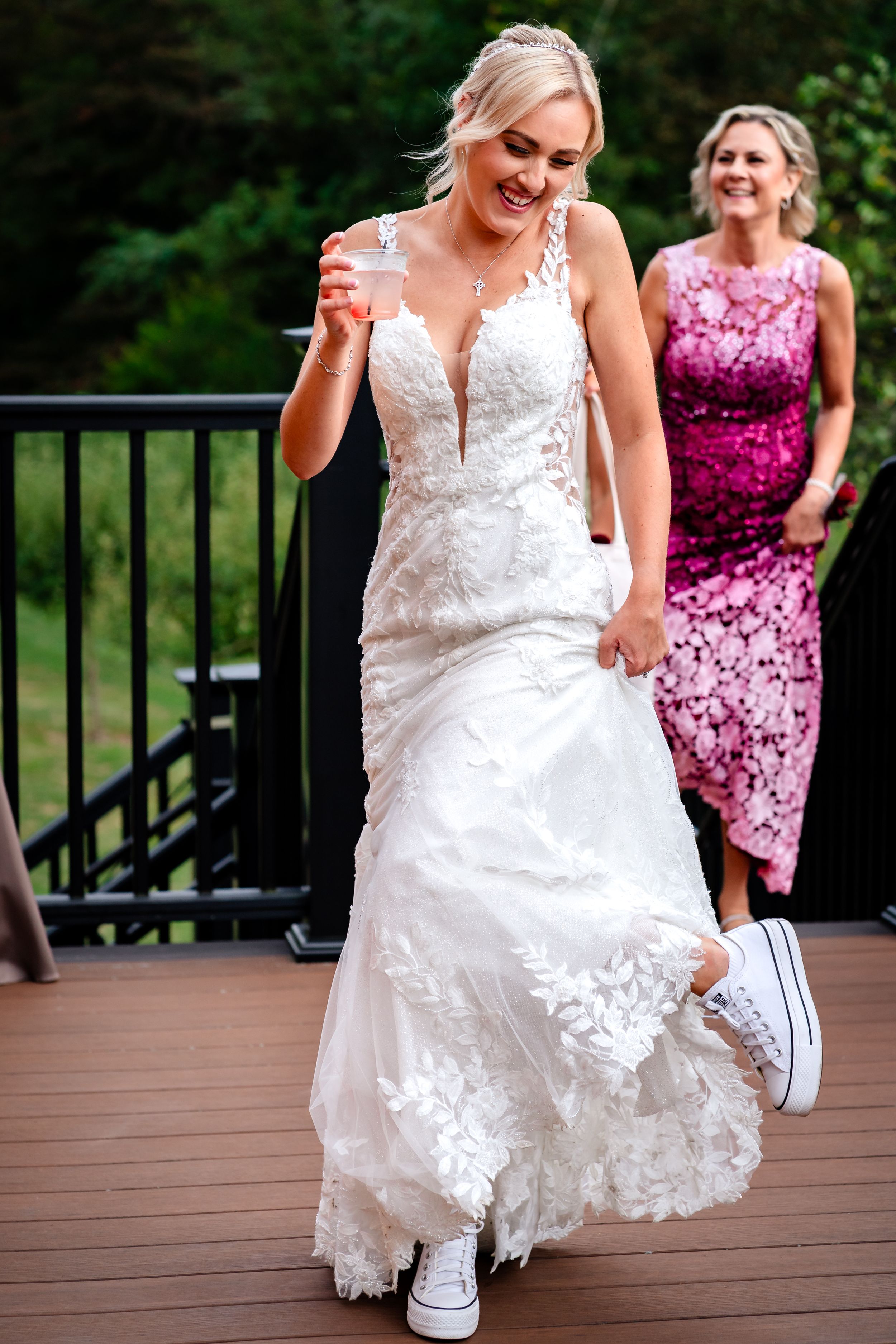 Wedding party on outdoor deck with bride in white lace dress and attendant in pink.