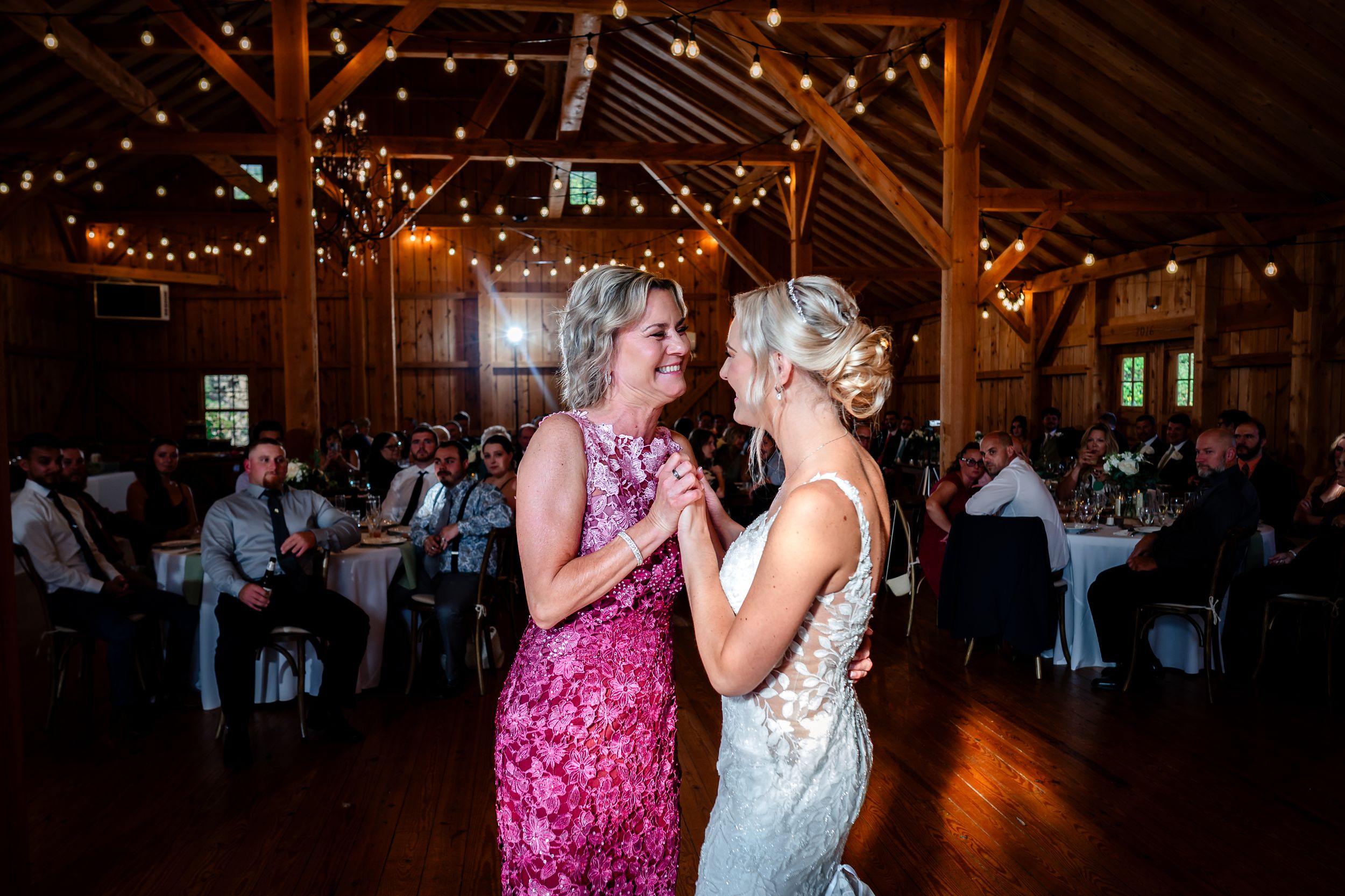 Wedding reception dance floor with guests celebrating under warm barn lighting.