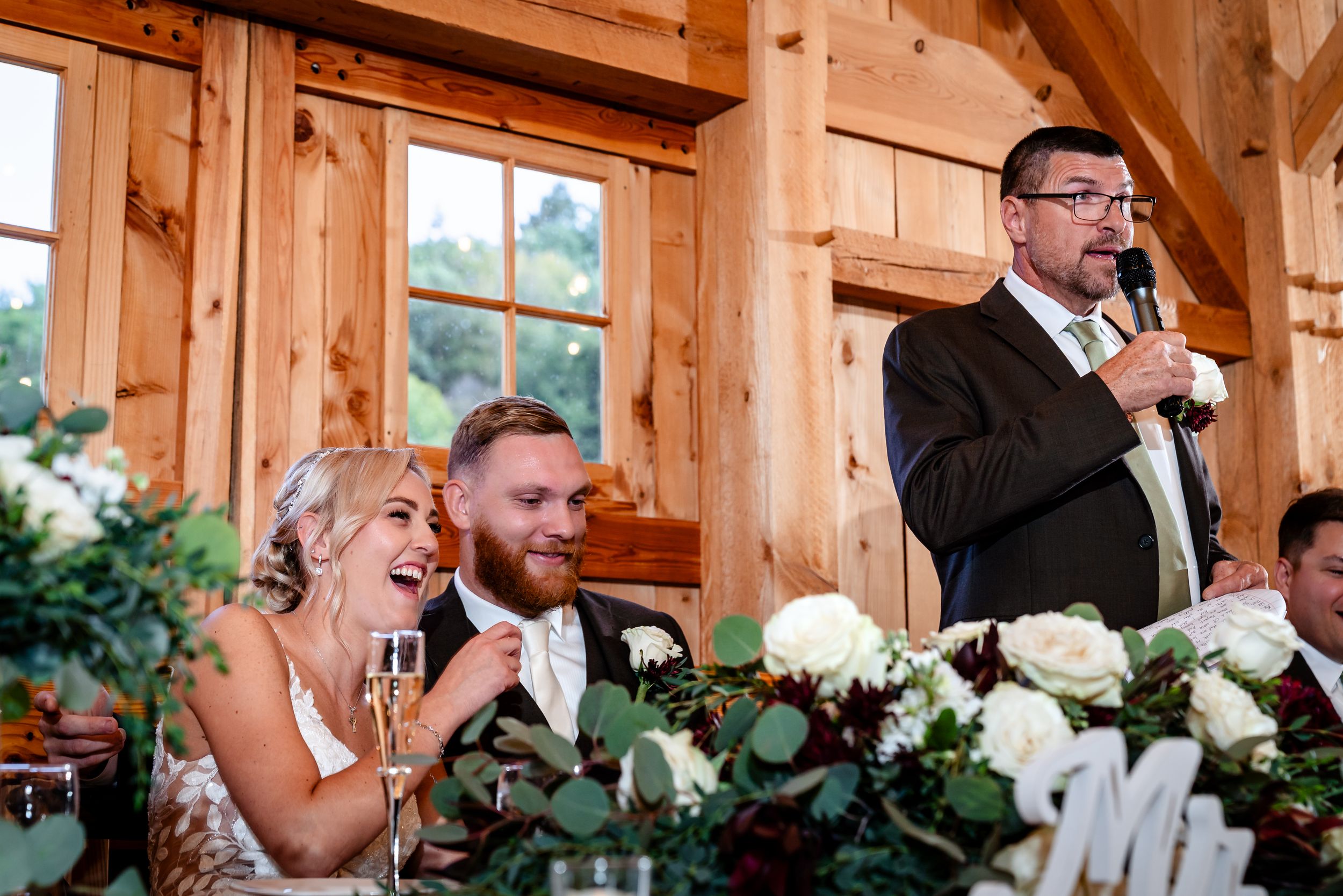 Wedding party toasting with champagne glasses inside rustic wooden barn venue.
