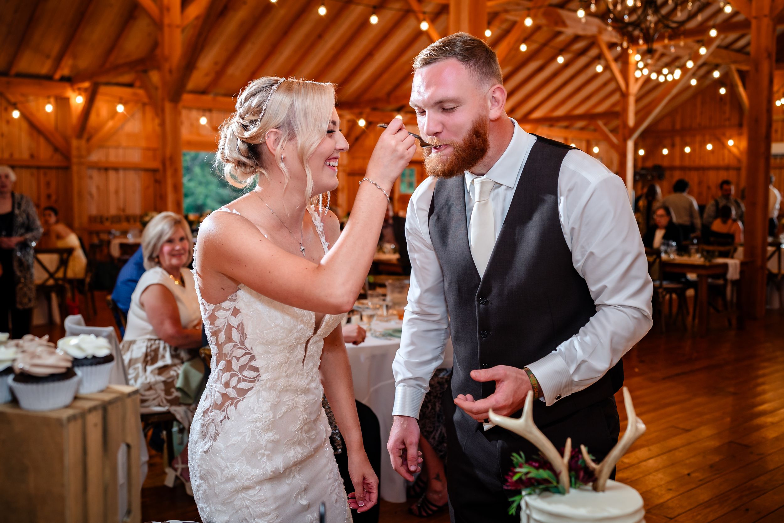 Couple dancing and celebrating at rustic barn wedding reception with warm lighting.