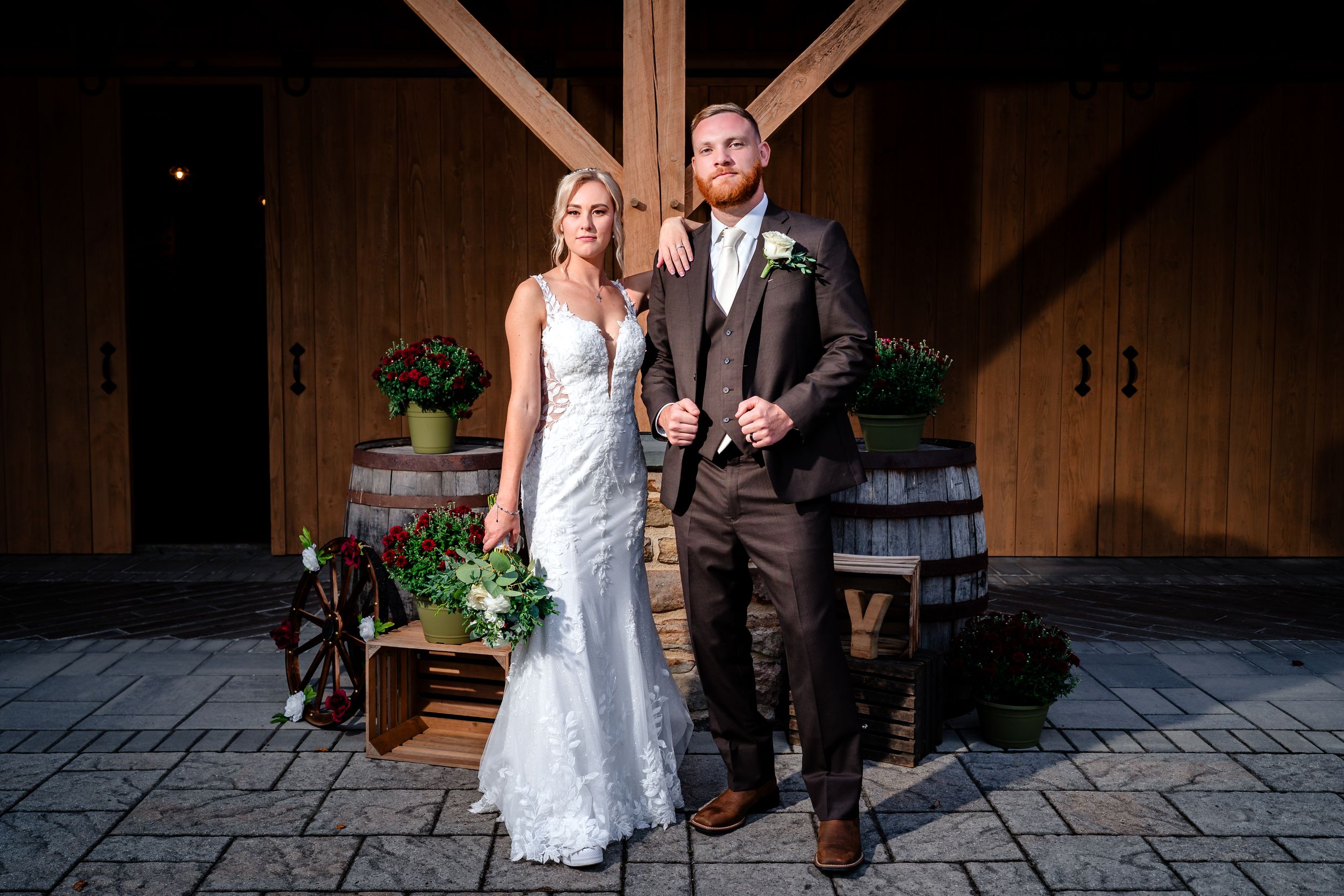 Romantic couple portraits against rustic barn backdrop during sunset.