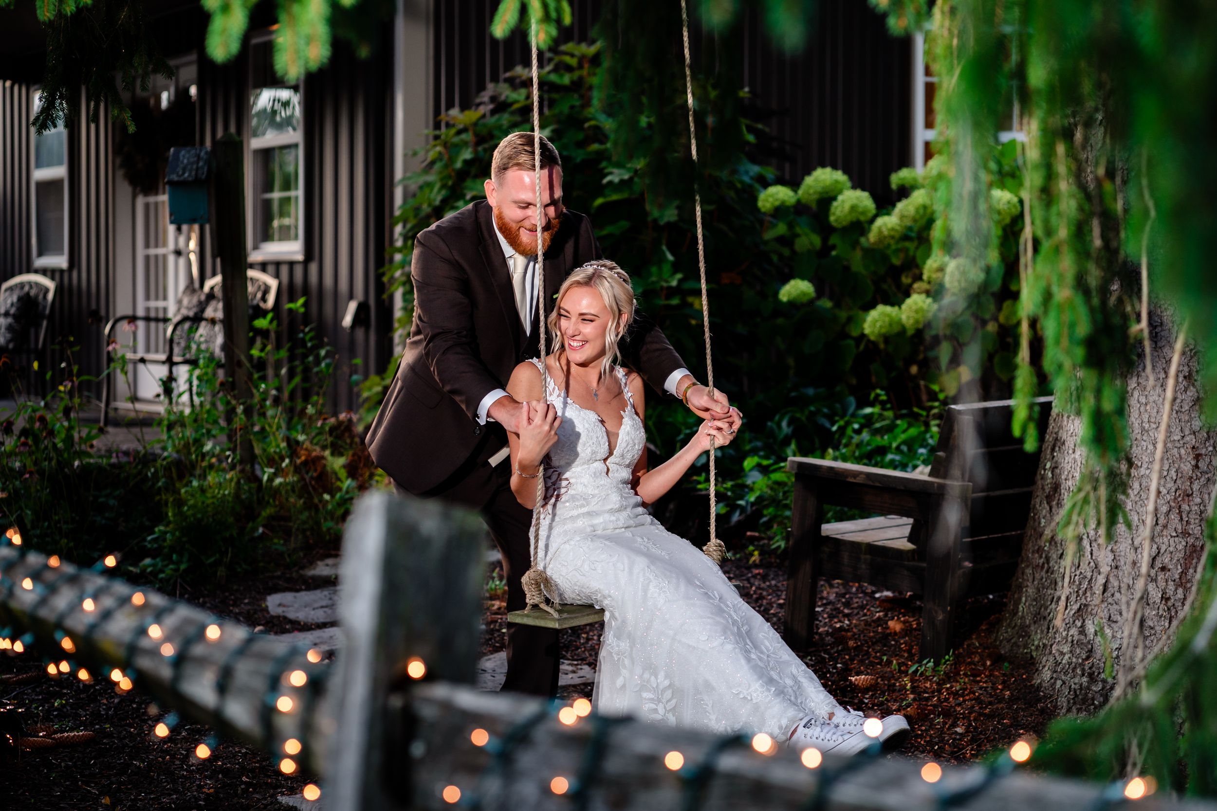 Romantic garden wedding portraits under hanging string lights and greenery.