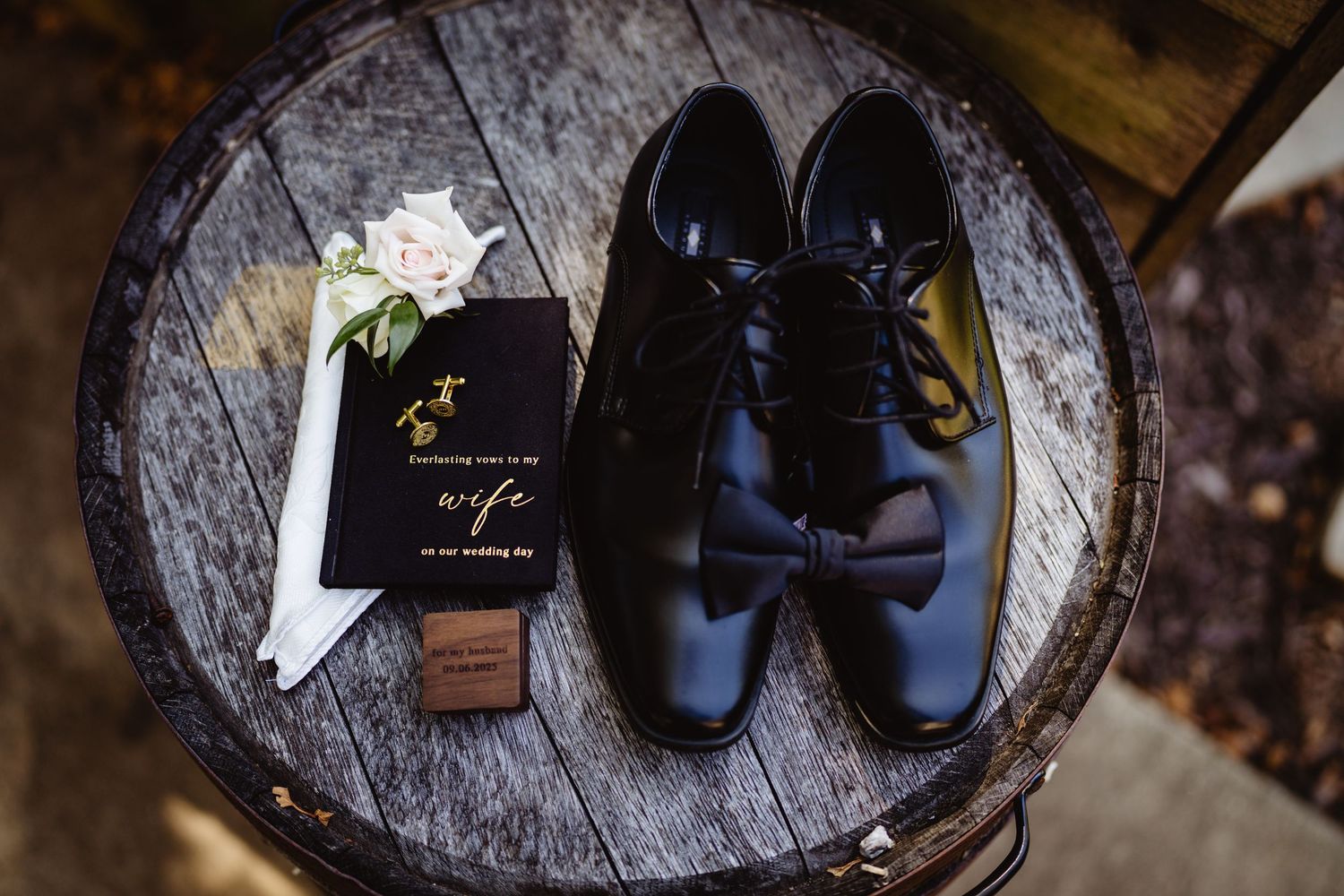 Black leather shoes and accessories arranged on rustic wooden surfaces for wedding preparation detail shots.
