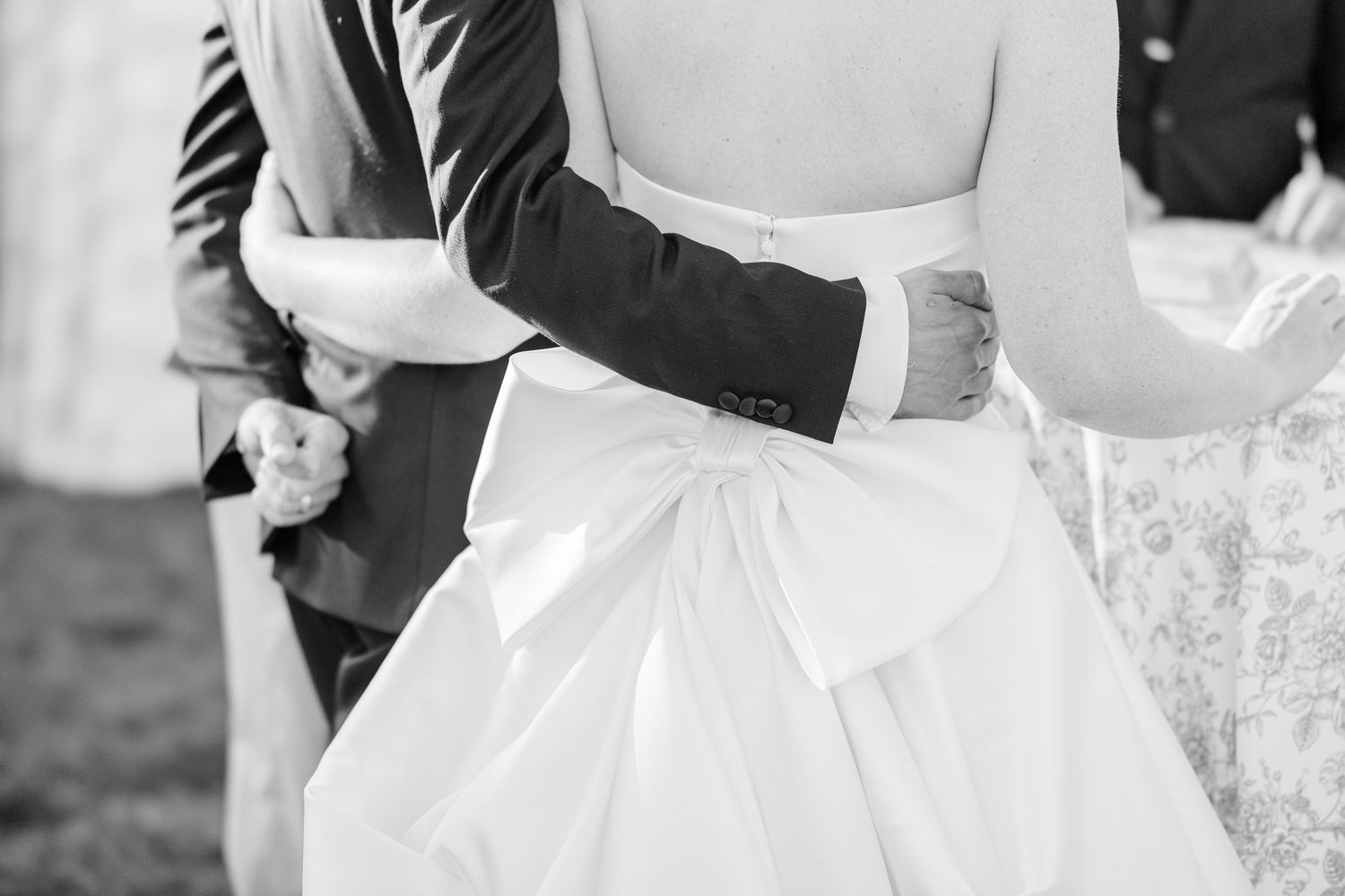 Black and white photo of a bride in a satin wedding gown with bow detail creating elegant silhouette.
