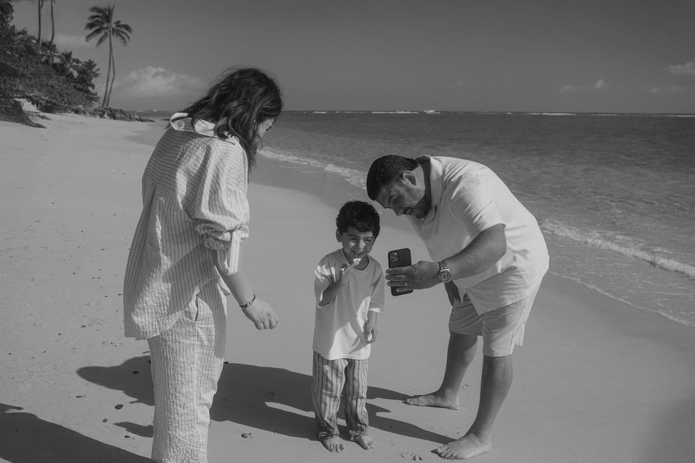 Beach scene with young family having fun collecting seashells and playing together in black and white.