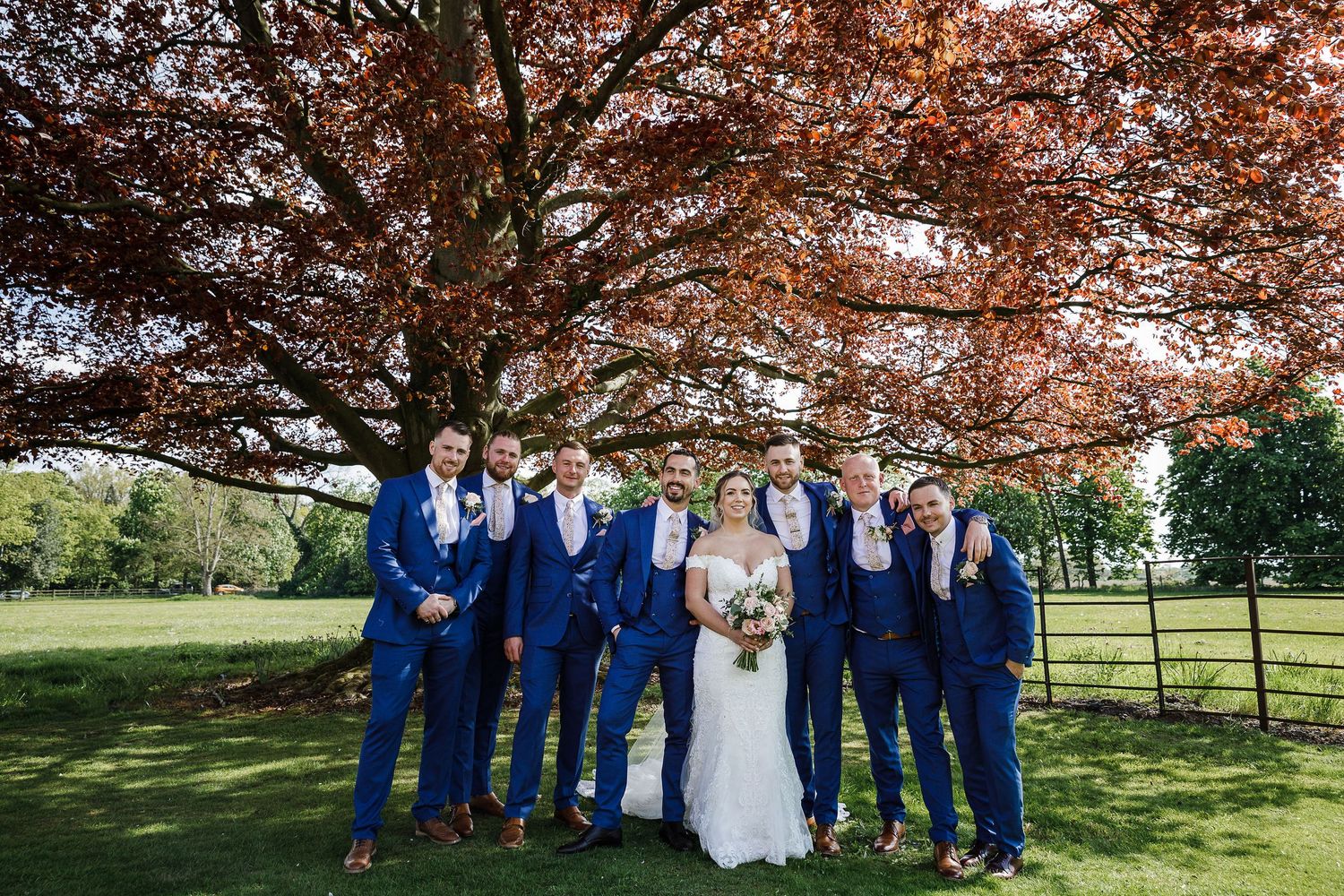 Wedding group photographed in the grounds of Kelham House with trees framing the scene