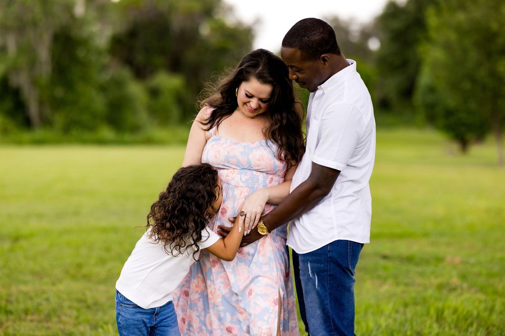 Family shares joyful embraces and laughter while posing together outdoors in a scenic park setting.