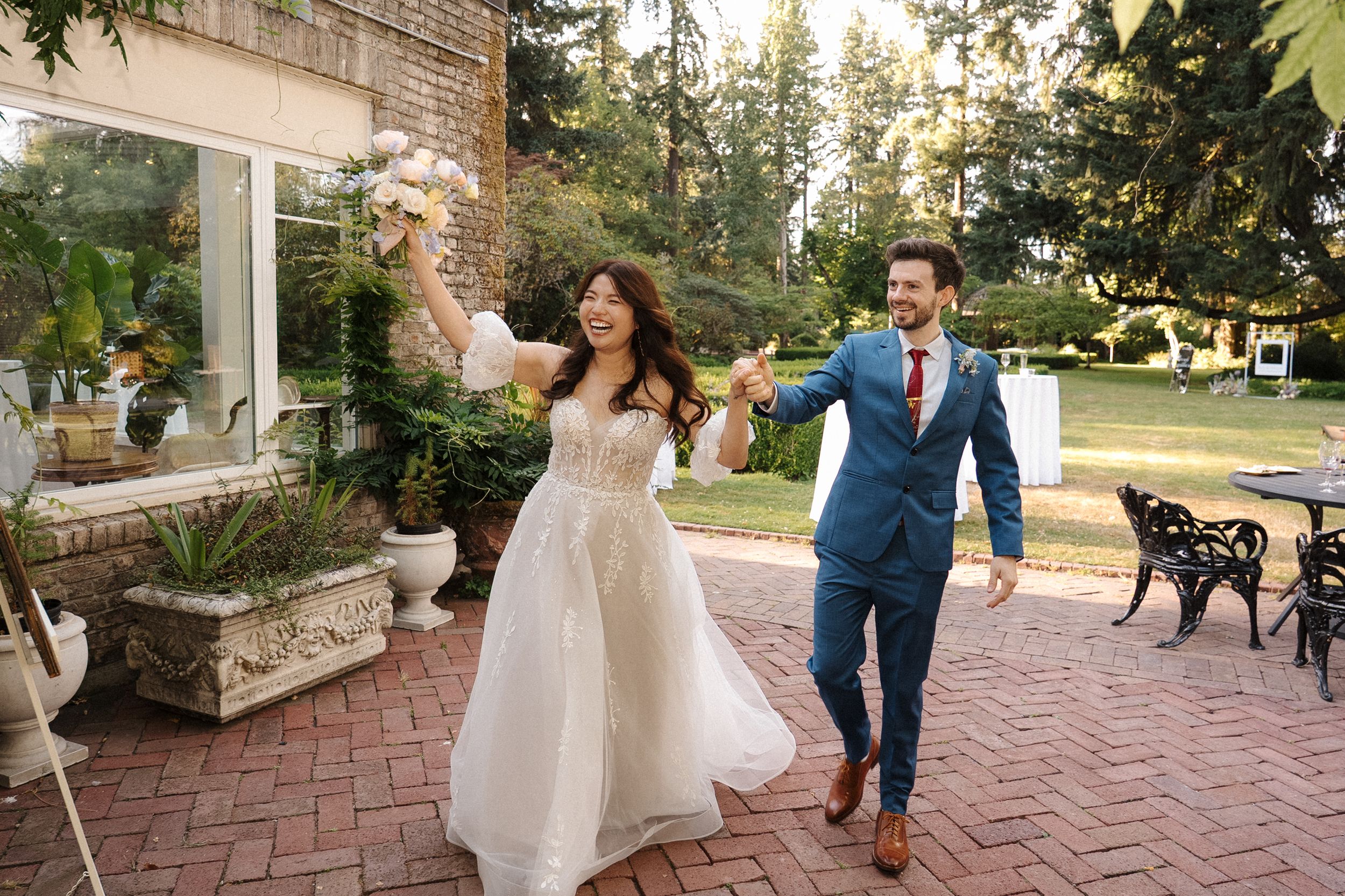 Wedding guests dancing and celebrating on a brick patio during an outdoor evening reception.