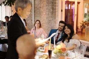 Reception guests engaged in lively conversation around an elegantly set dining table with glowing candles.