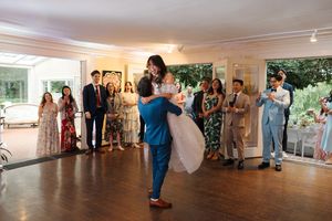 Dance partners gracefully practice swing dance moves across a wooden floor in a bright studio space with other dancers.