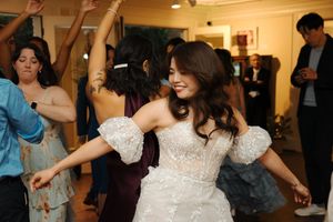 Wedding guests dance and celebrate together at a reception in a bright indoor venue decorated in classic style.