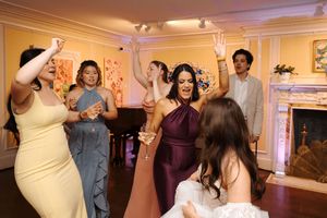 Wedding reception guests dancing and celebrating together on the dance floor at an elegant venue with warm lighting.