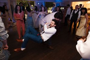 Wedding guests dance and celebrate together on a dimly lit dance floor at an evening reception.