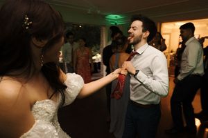 Guests celebrate and dance at a wedding reception with dimmed lighting and festive atmosphere.