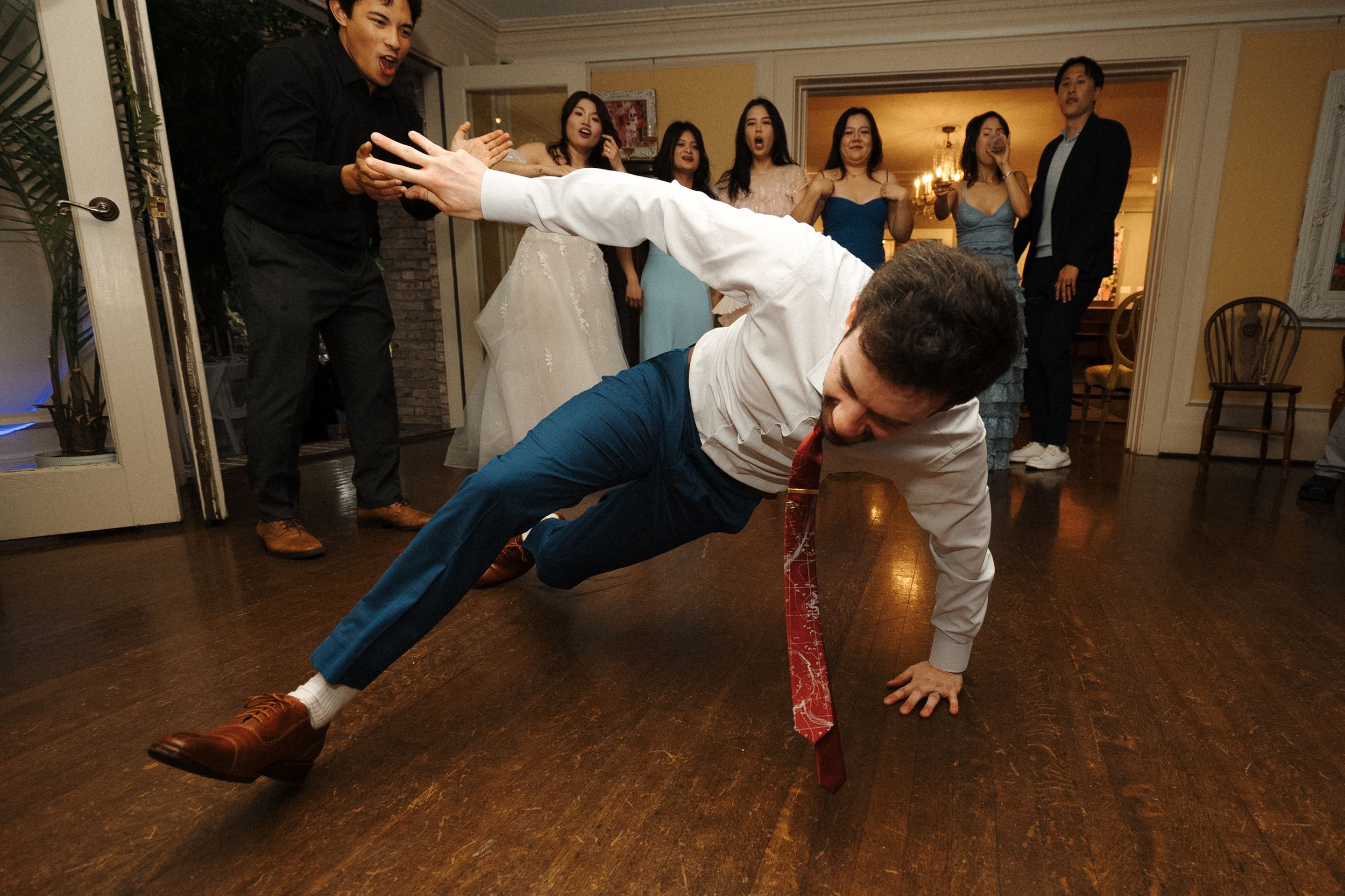 A breakdancer performs an athletic freeze pose while executing a dynamic move on a polished wooden floor.
