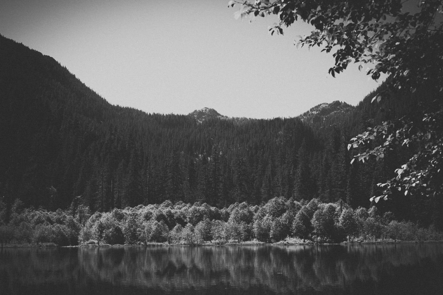Black and white landscape of mountains reflecting in still lake.