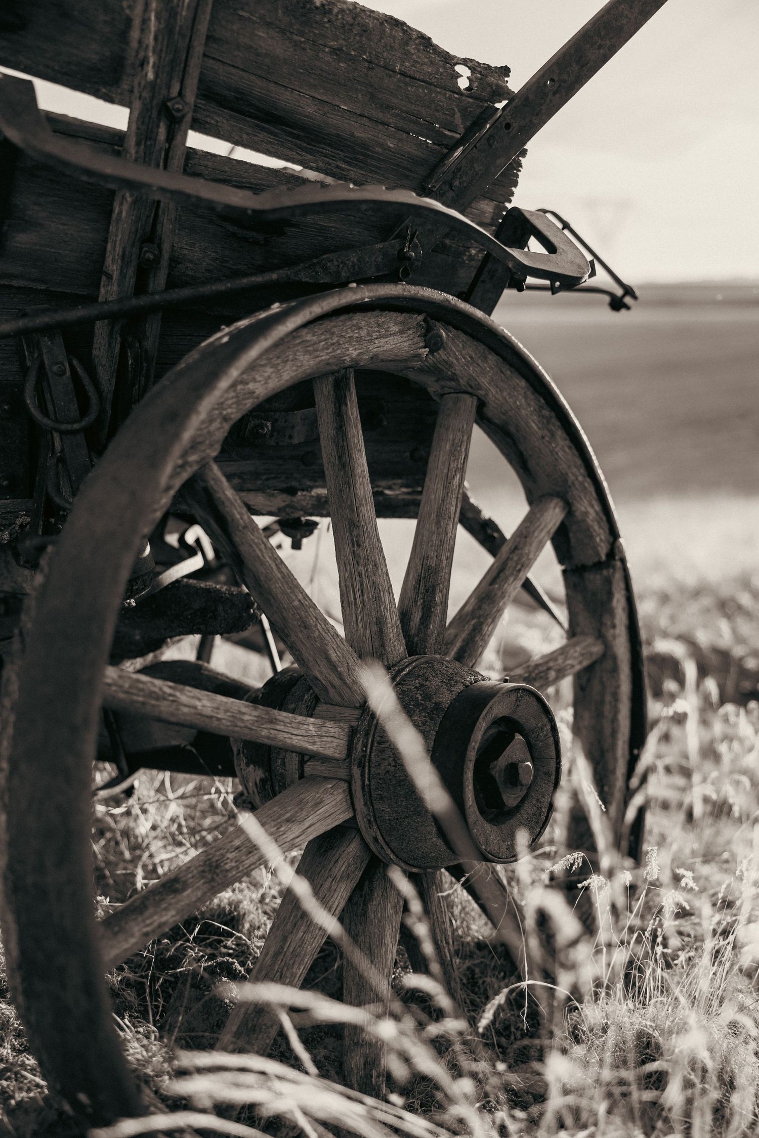 Vintage wooden wagon wheel in sepia tones against rustic background.