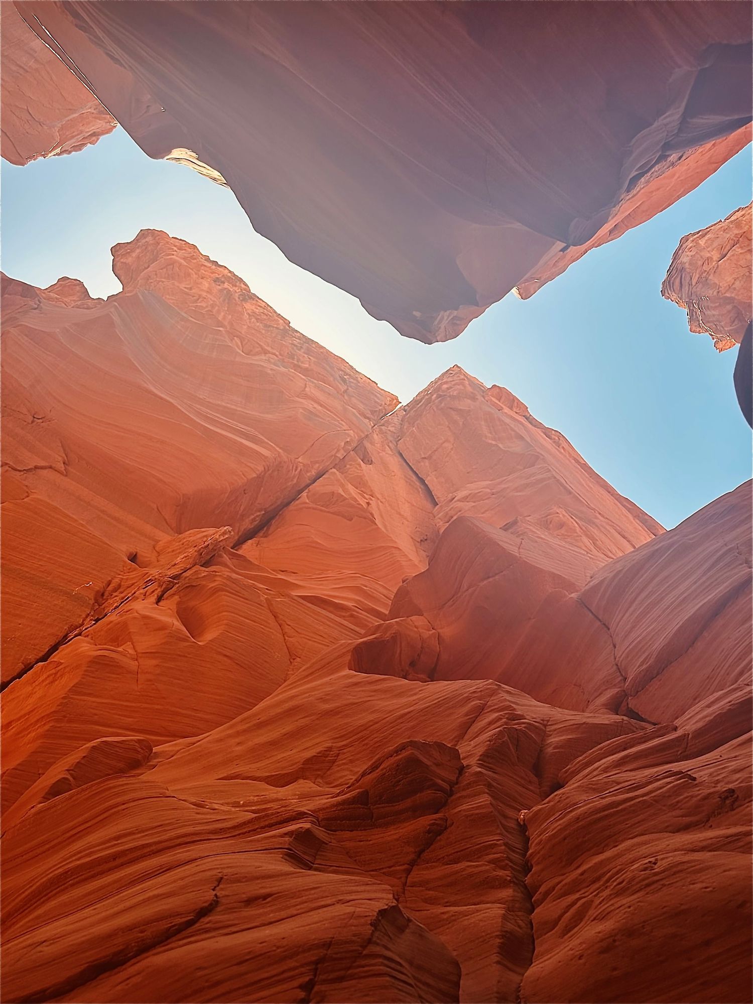 Dramatic view of red sandstone canyon walls against bright blue sky in slot canyon.