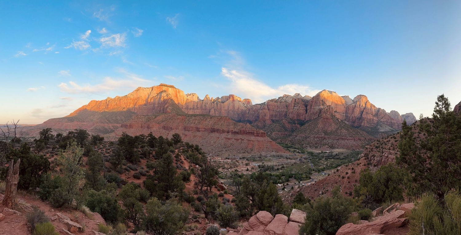 Panoramic view of red rock mountains under bright blue sky.