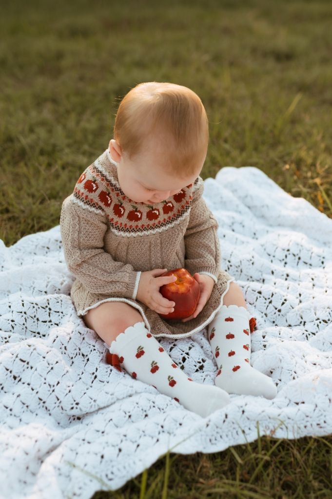 A sequence of images showing a person sitting on a white lace blanket outdoors eating a chocolate cookie.